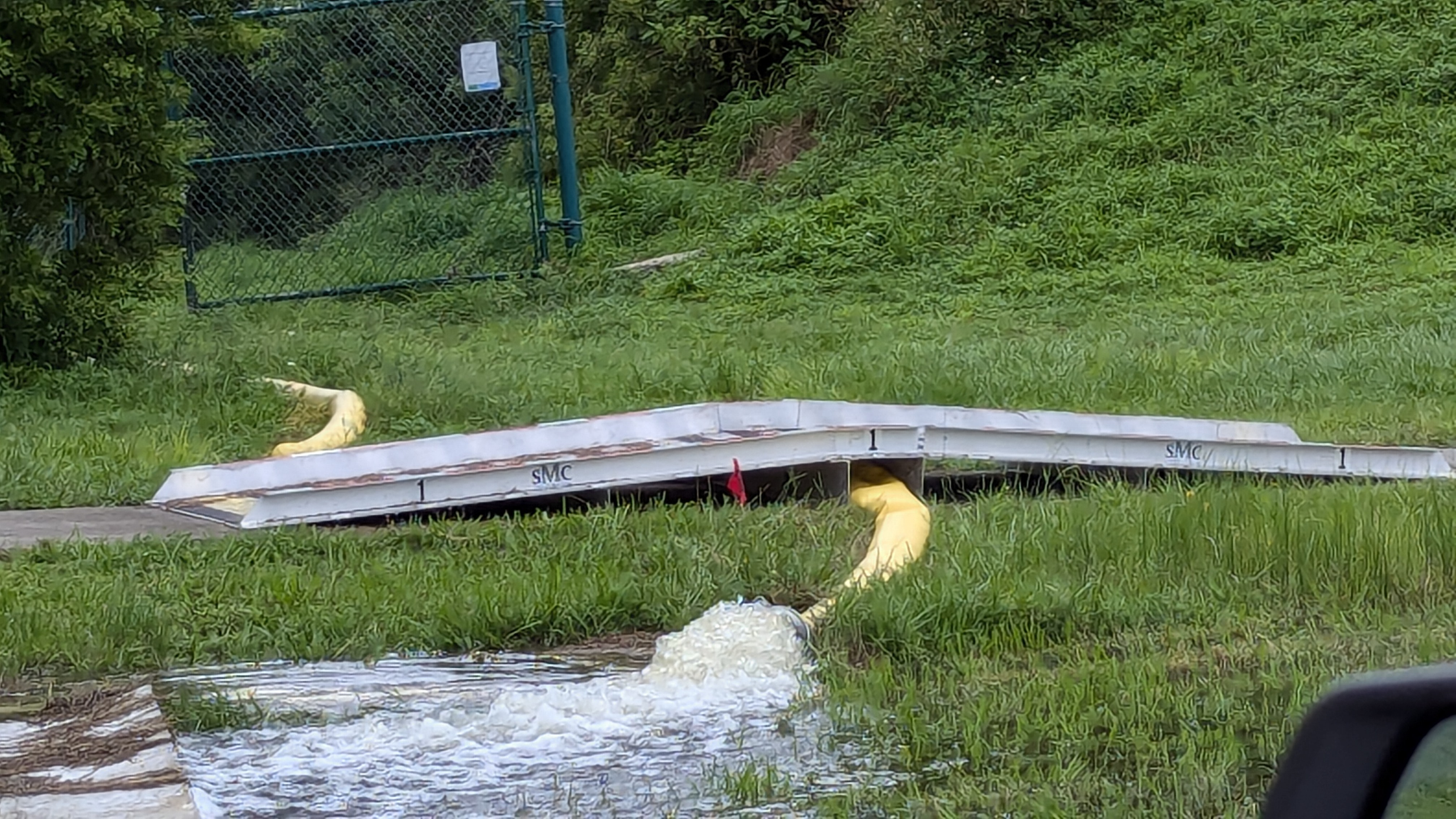 A sidewalk ramp in action showing a hose pumping water under sidewalk ramp